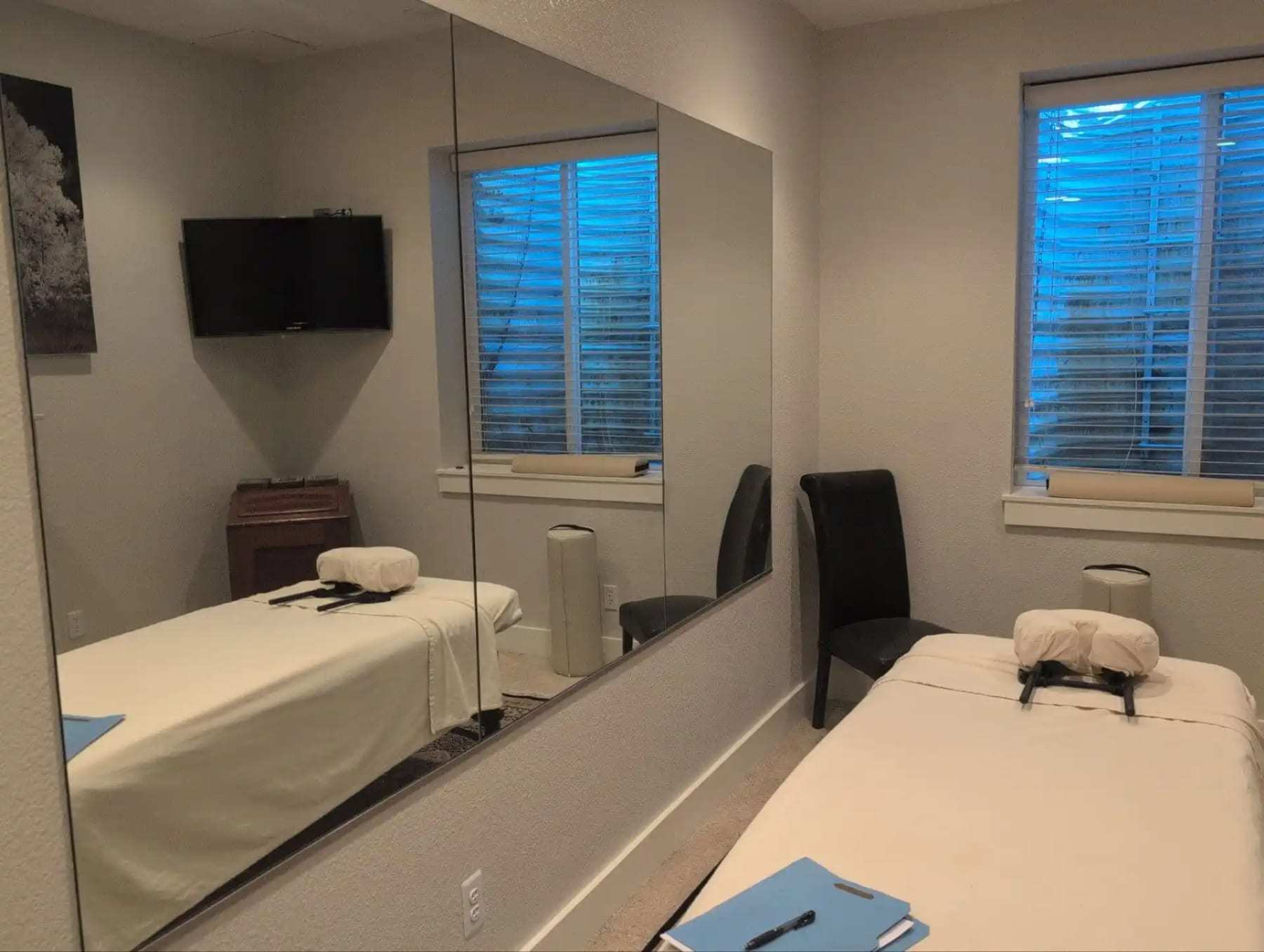 Treatment room with two massage tables and a wall mirror