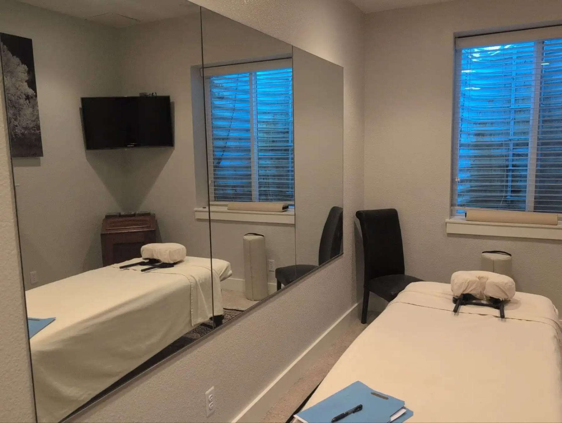 Treatment room with two massage tables and a wall mirror